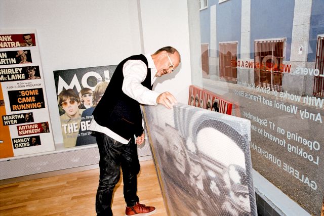 Portrait of Martin Steppacher. Paintings by Steve Alan Kaufman. Technique: hand painted oil on canvas silkscreen; from left to right: Film Poster 2002, The Beatles 2004, John and Yoko 2005, Painting behind Yoko and John: The Beatles Debut on Ed Sullivan 2006, Photo Patrick Walter, Courtesy: Gallery Durchgang