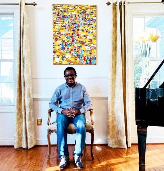Photo of artist and collector Olusanya Ojikutu with “Market Lane,” a 2013 painting by Ablade Glover, in his home, which serves as a sanctuary for traditional, modern, and contemporary African art. Photo courtesy of Cara Ober for Bmore Art magazine.